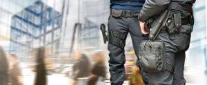 Armed policemen on guard in busy street with modern glass buildings and people walking