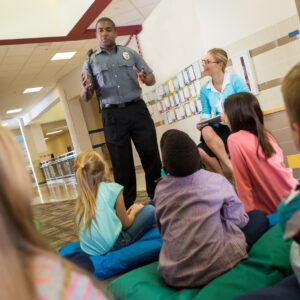Police officer at school speaking to young students about safety.